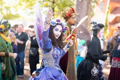 Woman waving from a parade dressed as a fairy