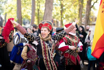 Woman waving from a parade dressed as Renaissance-era nobility