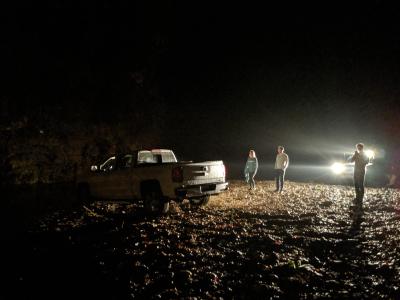 People gathered around a truck stuck in a riverbed