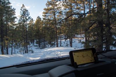 Looking over the dashboard of a car headed down a snowcovered trail